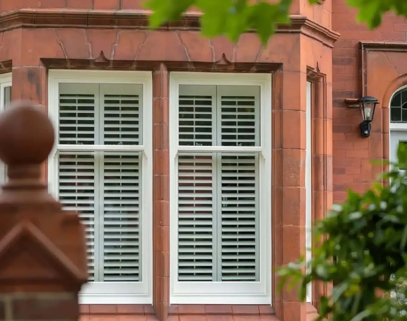 uPVC window showroom in Aberdeen, Scotland, showing white and anthracite framed double-glazed windows in a modern display setting. White sash windows with plantation shutters on a red sandstone home in Scotland.